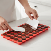 Using spatula to fill mold with chocolate
